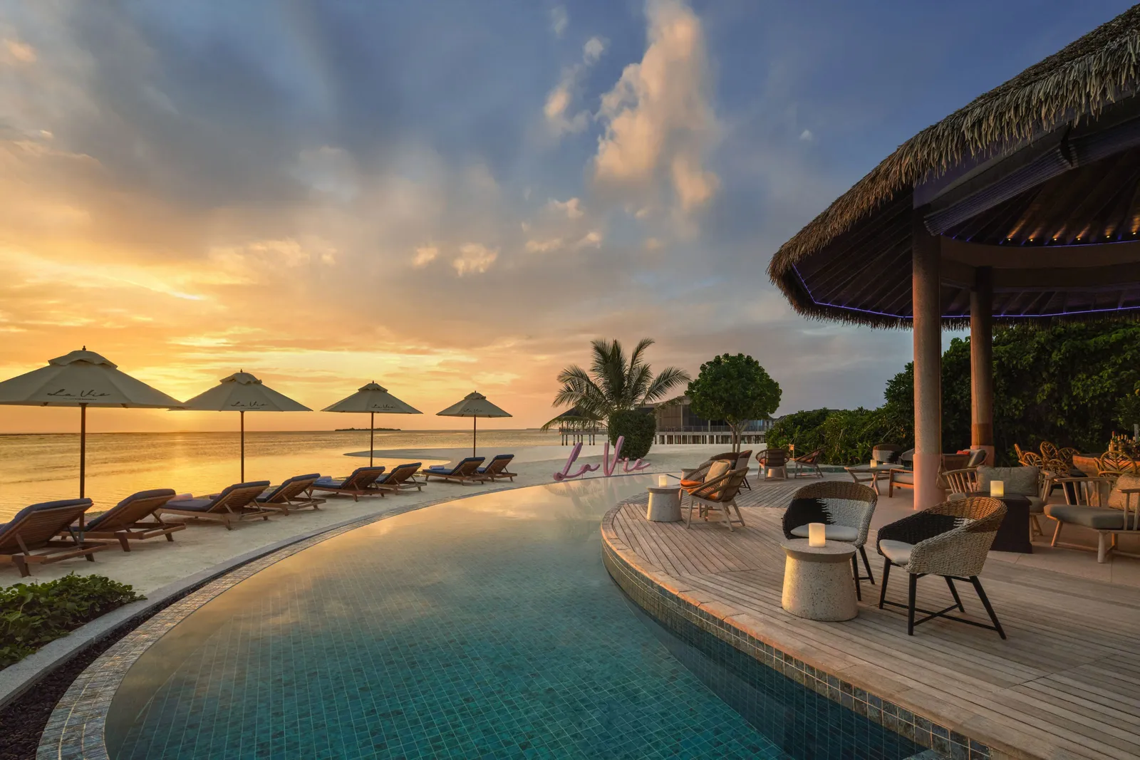 La Vie’s infinity pool at sunset, with loungers and parasols