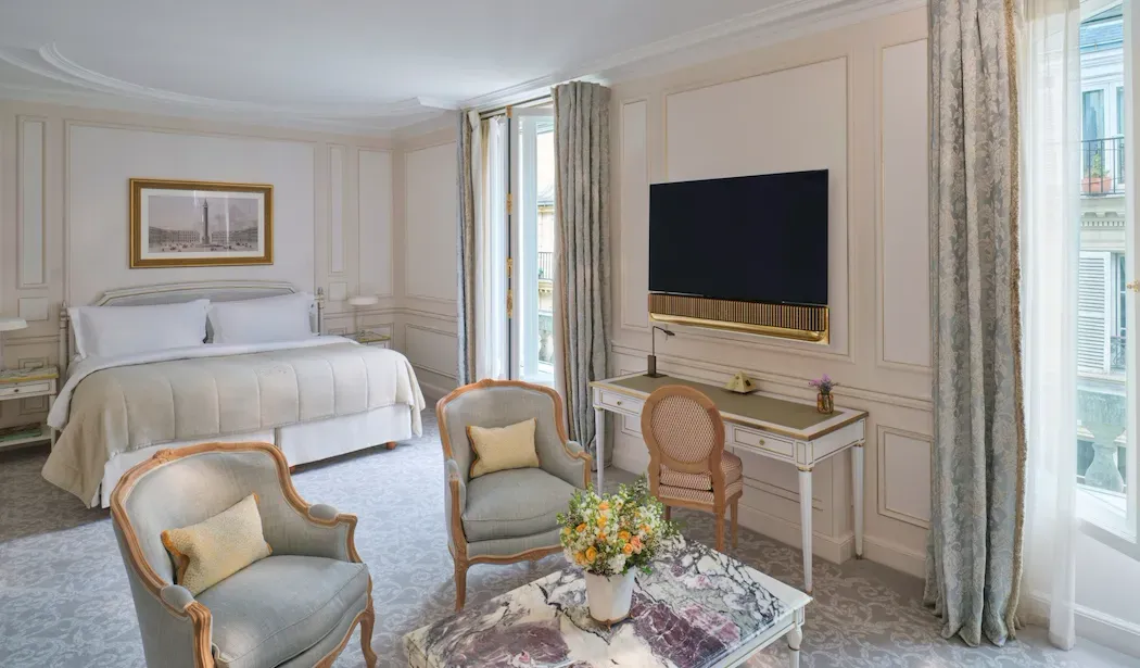Deluxe Junior Suite at Le Meurice, with 2 armchairs and an inlaid table between the bed and television