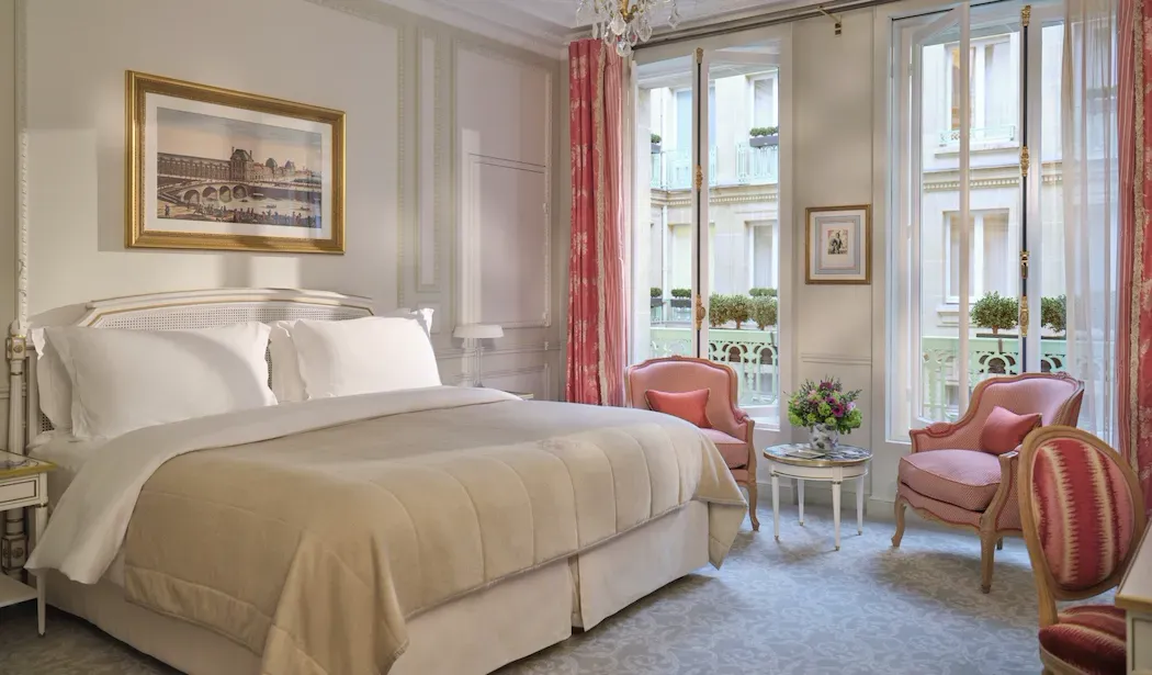 Deluxe Room at Le Meurice, with a bed, pink armchairs and tall windows framed by pink curtains
