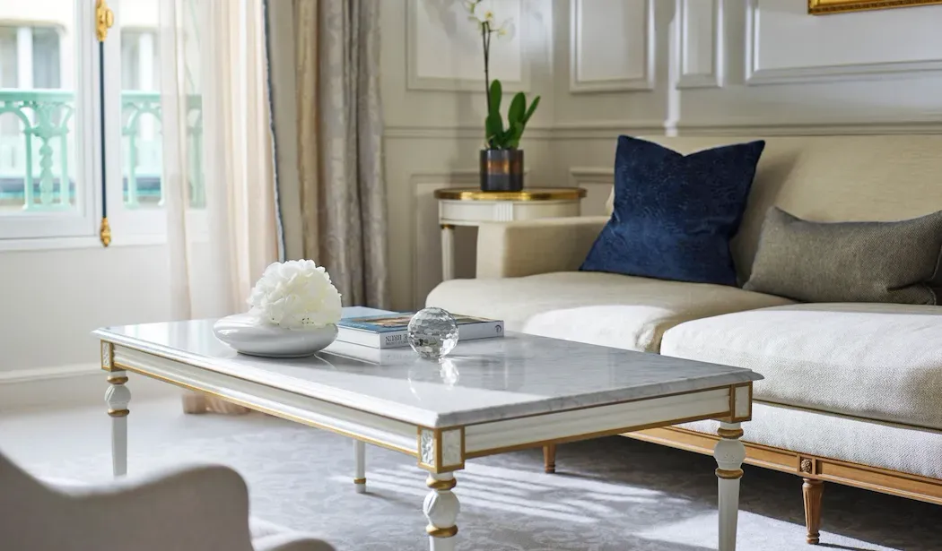 Deluxe Suite at Le Meurice, with a cream sofa, dark blue cushion and marble-topped coffee table