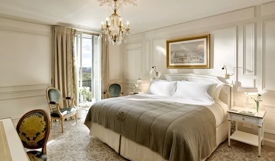 Executive Room, Eiffel View at Le Meurice, with a chandelier, cream bed linen and chairs beside a tall window