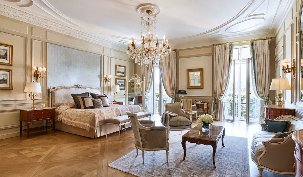 Presidential Apartment Tuileries, Park View at Le Meurice, with a bed and sitting area beneath a chandelier, framed by draped curtains