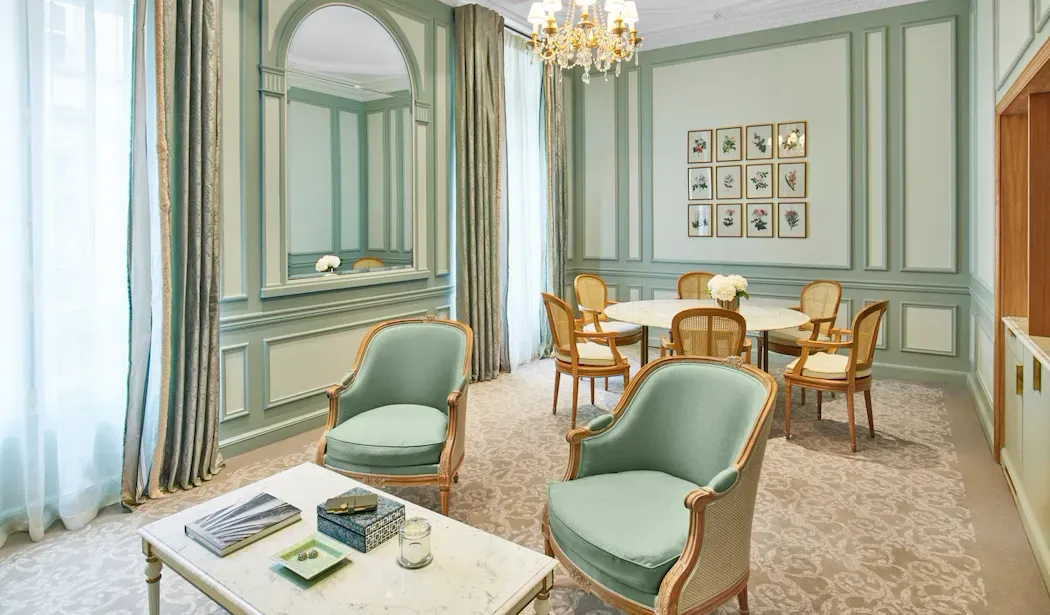 Superior Suite at Le Meurice, with green panelling, 2 armchairs and a round dining table beneath a chandelier