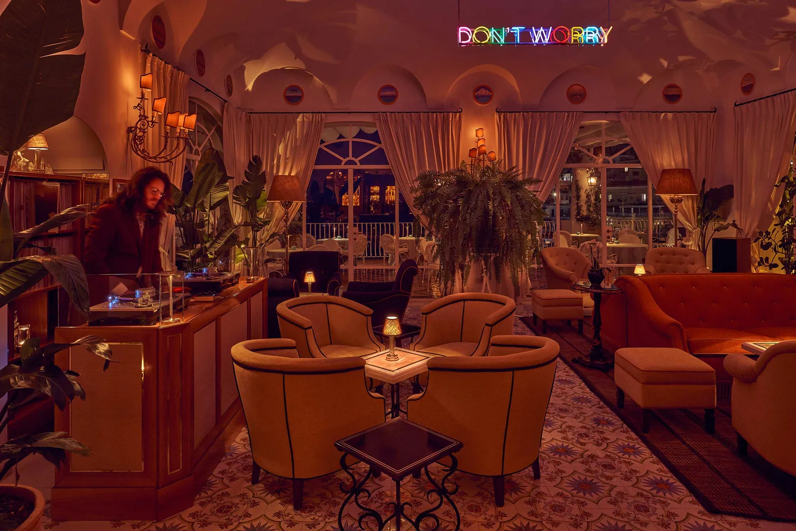 The Don’t Worry Bar: orange velvet armchairs, plants, rugs and the neon DON’T WORRY under the vault.