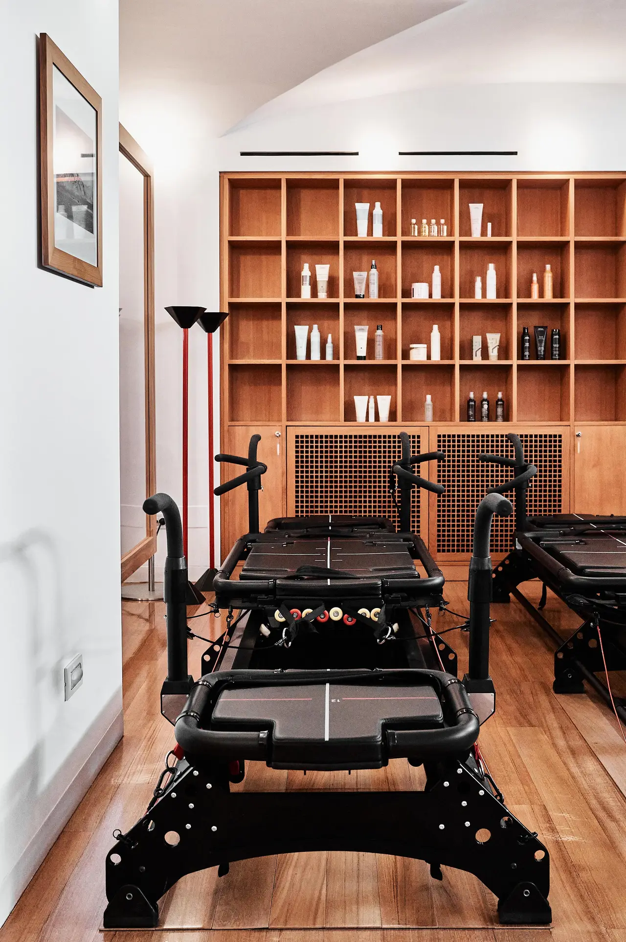 A Megaformer in the gym, beside a wooden bookcase of training kit.