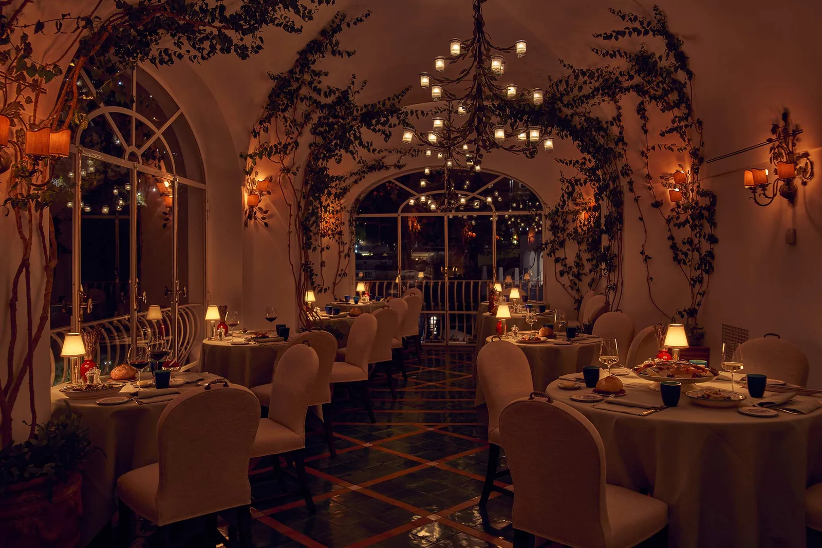 La Sponda in the evening, candles hung from the vault and the tables laid under the climbing plants.