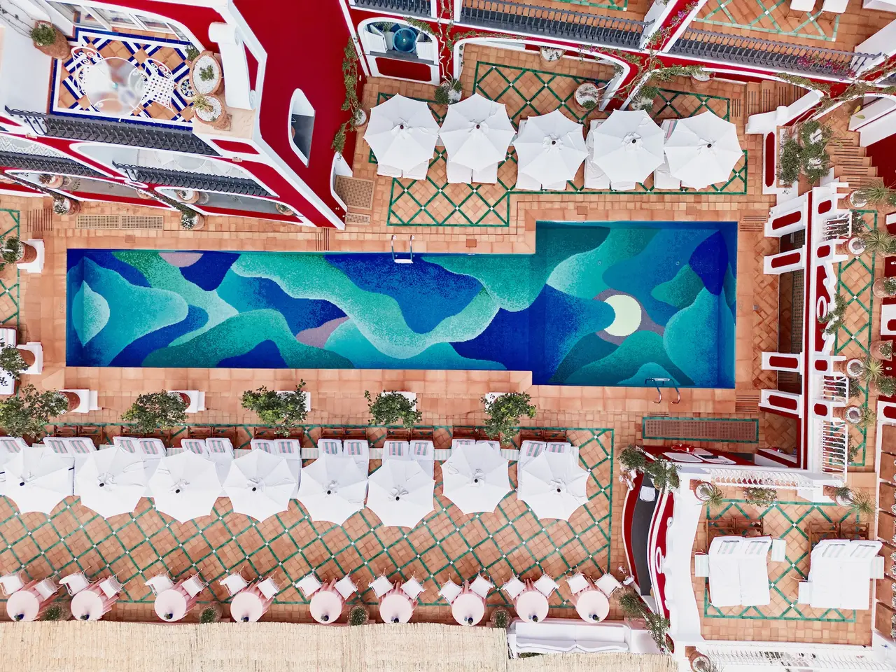 The pool terrace from above: the mosaic, the white loungers and parasols, the majolica floor.