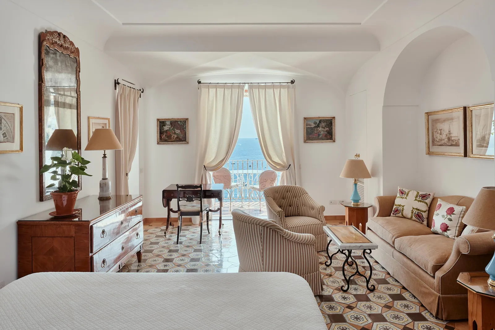 An Executive Sea View room: the sitting area with sofa and armchairs, an antique desk and the window onto the sea.