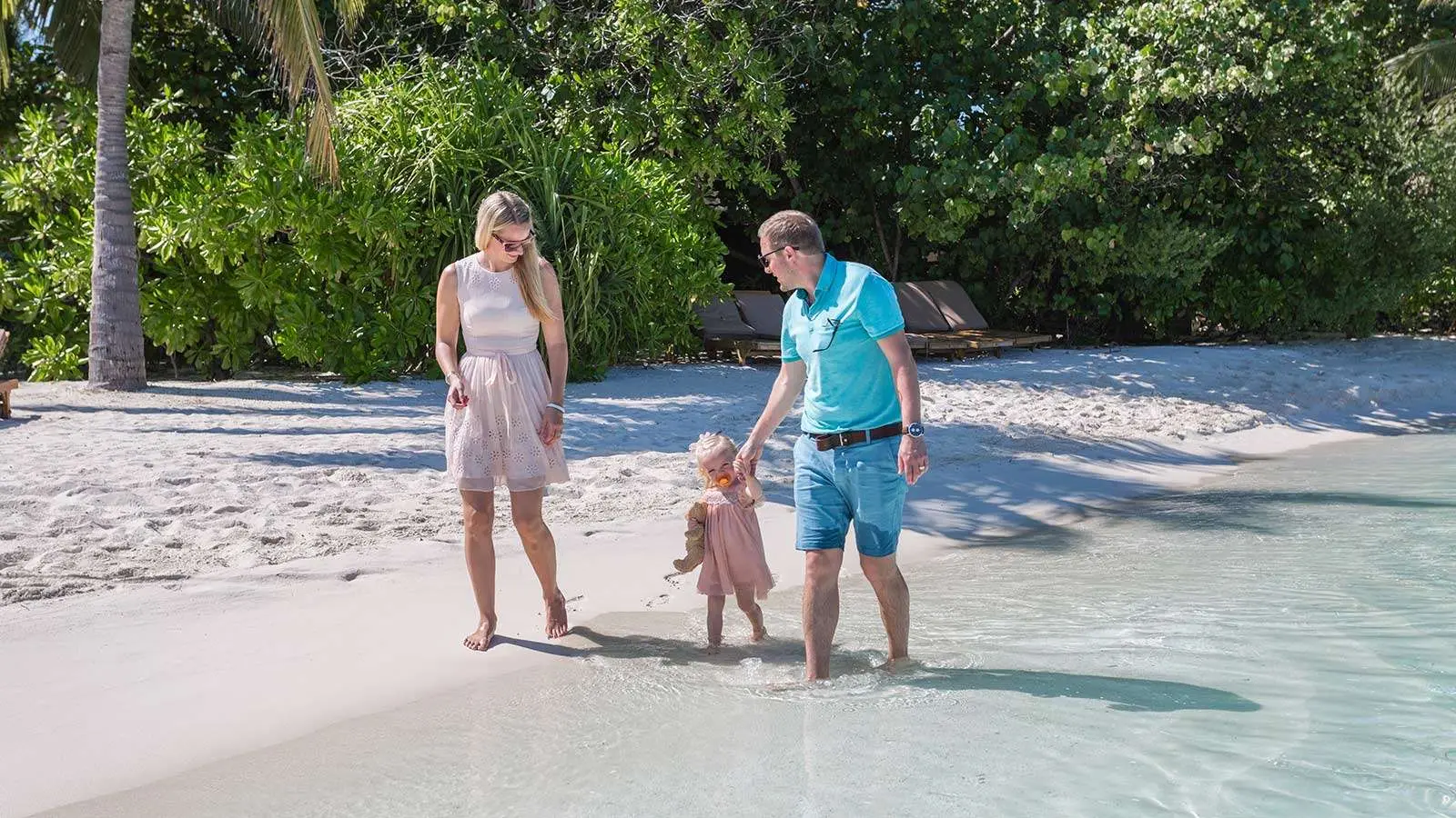 A family with a small girl on the white beach