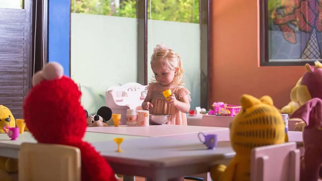A little girl at a table in the Turtle Kids Club, among soft toys