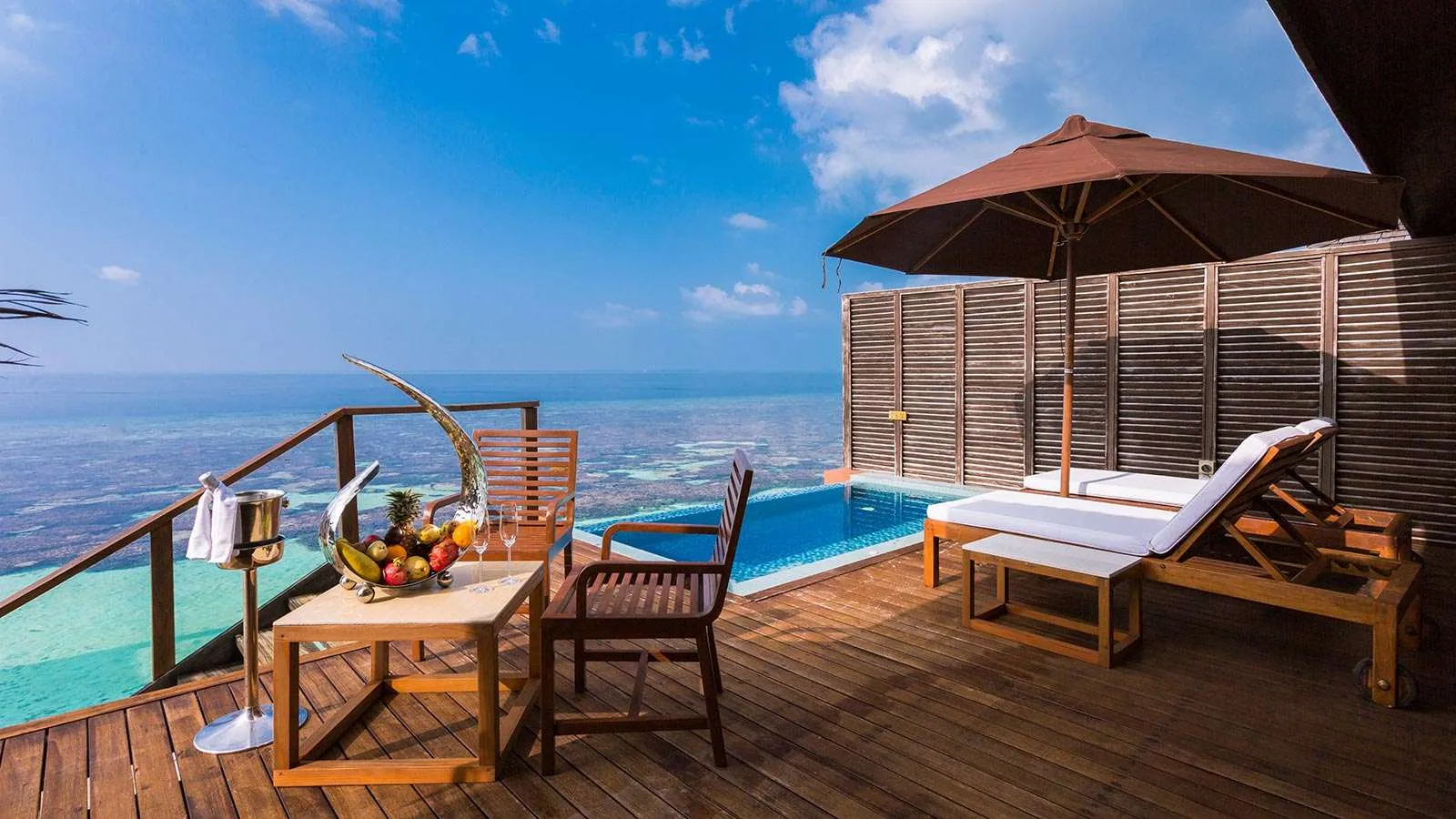 A Deluxe Water Villa’s deck, its jacuzzi pool and loungers over the sea