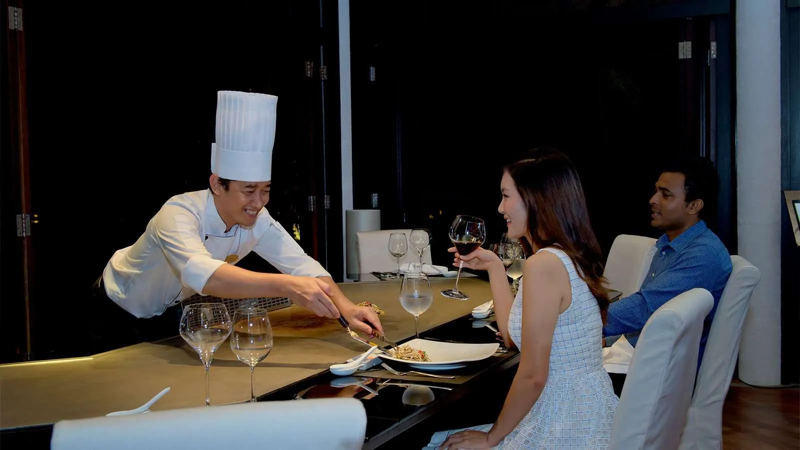 A teppanyaki chef cooking for a couple at AQVA