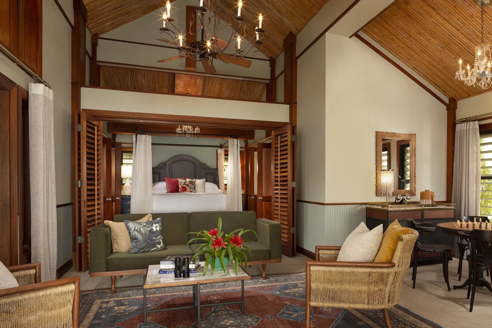 An Island Grand Suite: the living room with its green sofa and, through the open louvred doors, the four-poster bed.