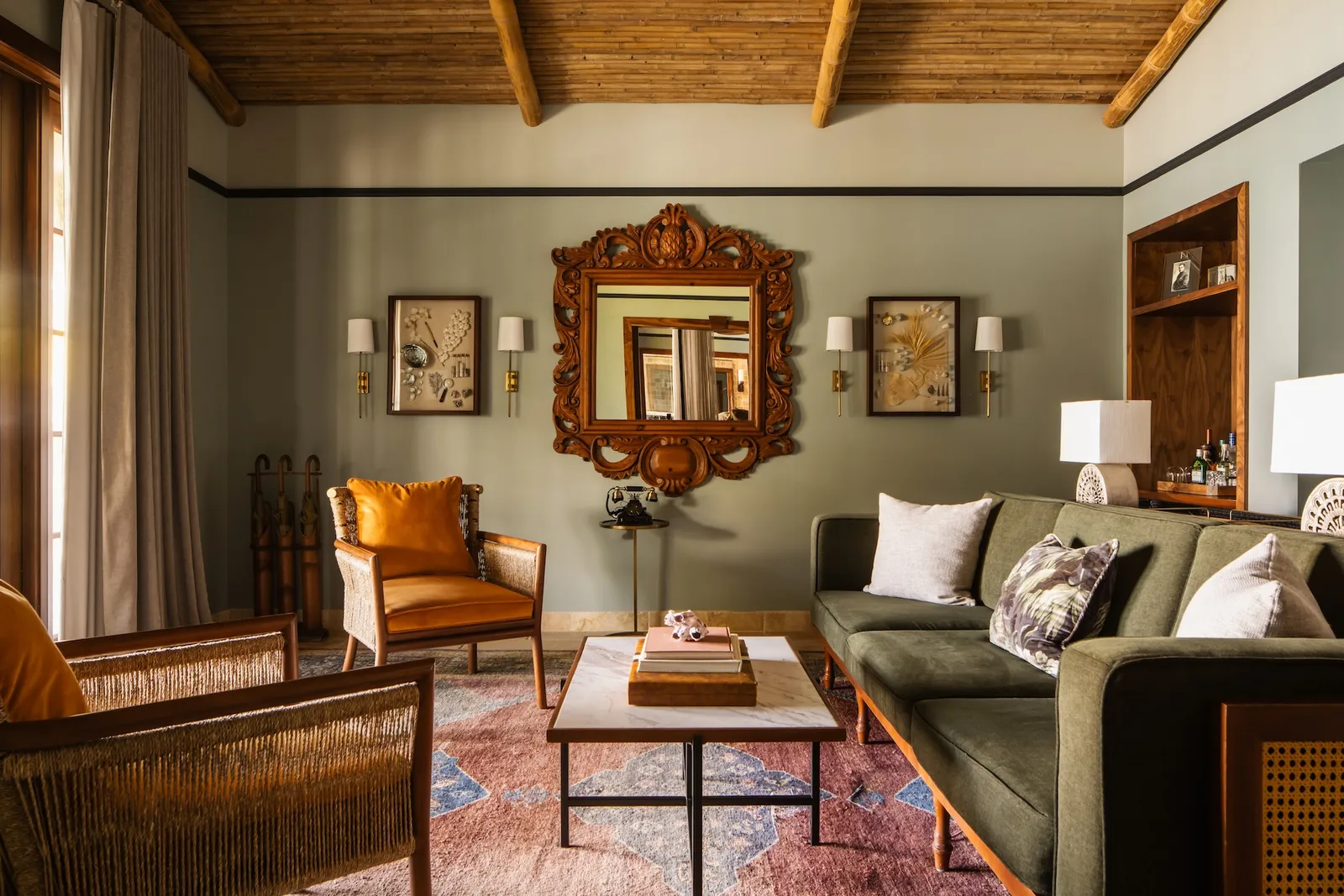 An Island Premier Suite’s living room: a carved mirror above the sofa, a leather armchair and the ceiling’s exposed beams.