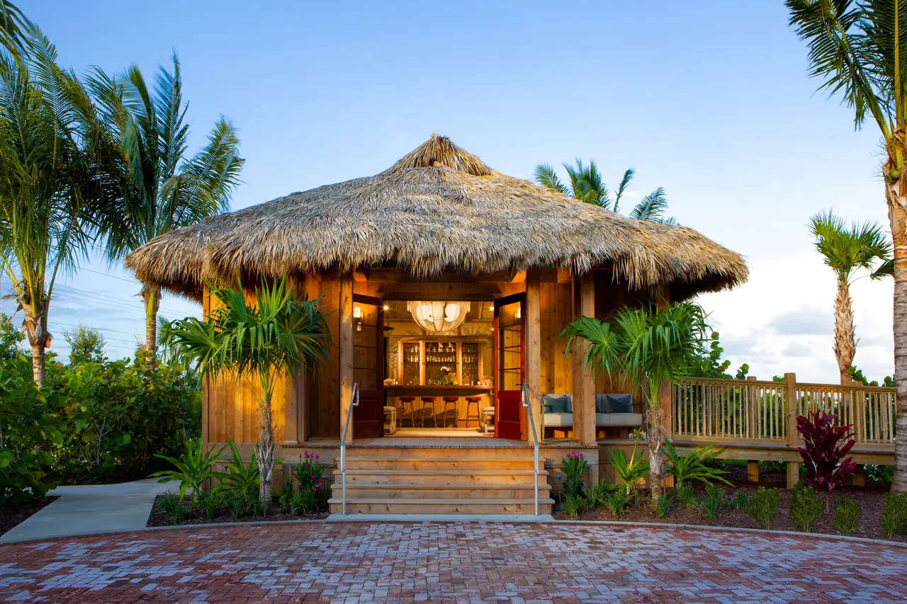 The Shore Station on Little Torch Key: a timber pavilion with a thatched roof, steps up to the door and palms either side.