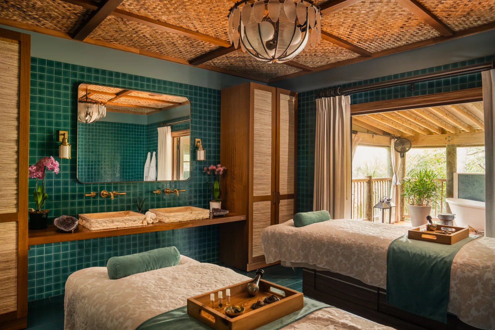 A double treatment room at SpaTerre: 2 massage tables, teal-tiled walls and a door open to a verandah.