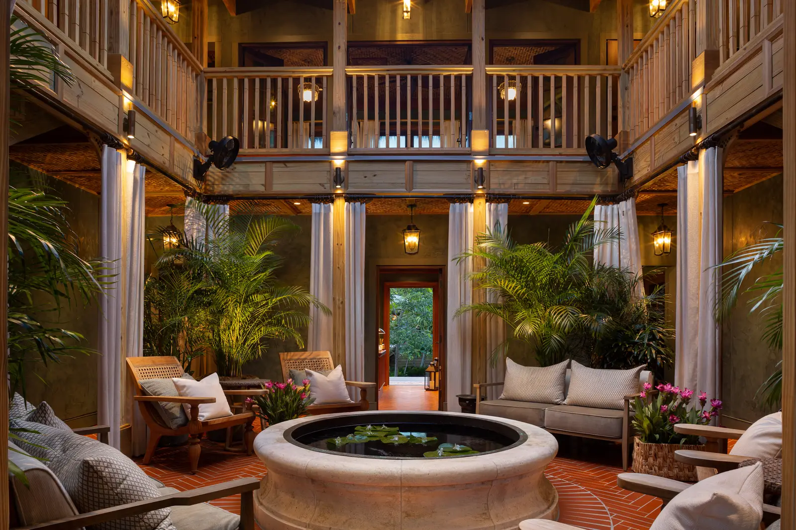 SpaTerre’s 2-storey atrium: a round stone pond in the middle, armchairs and sofas about it, timber galleries and ferns.