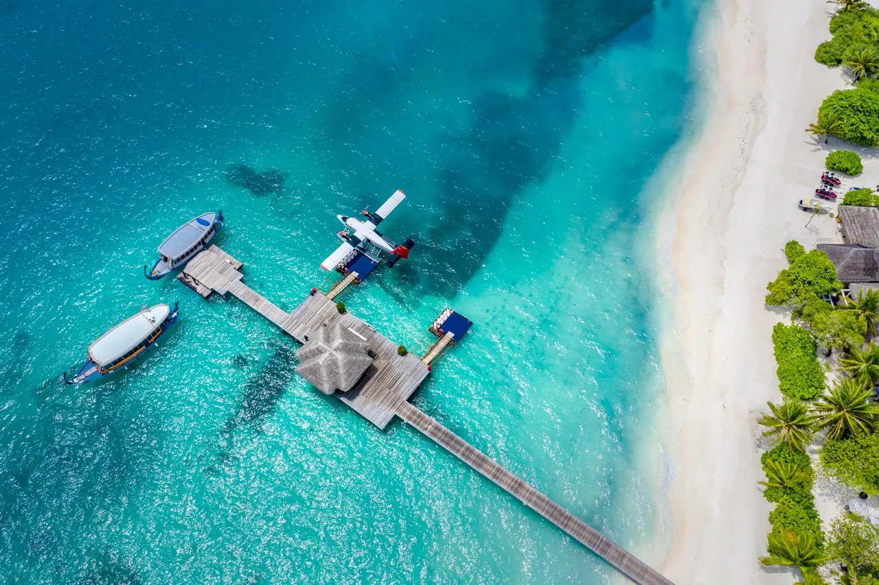 The seaplane jetty from the air, a seaplane and a boat on the turquoise lagoon