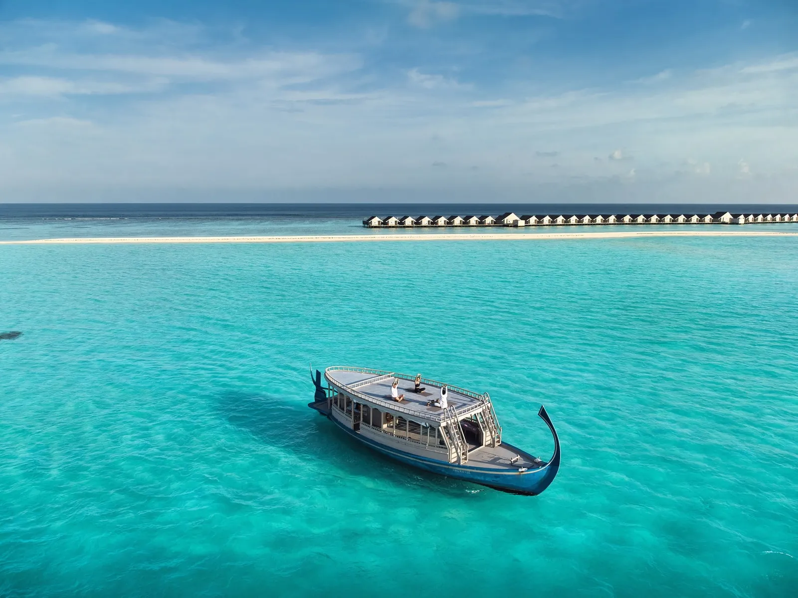 A dhoni moored in the lagoon, the overwater villas on the horizon