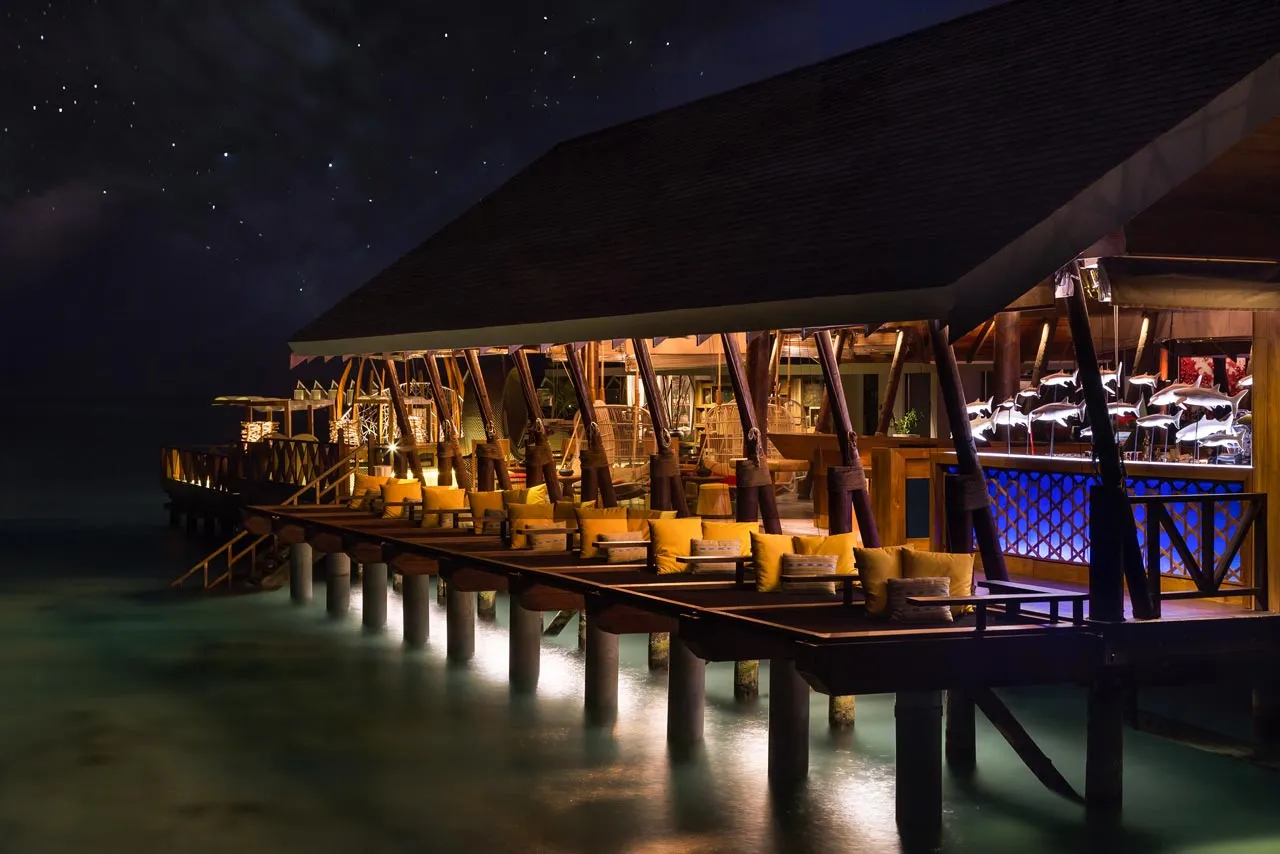 The EAST Bar at night, lit up on its stilts over the lagoon