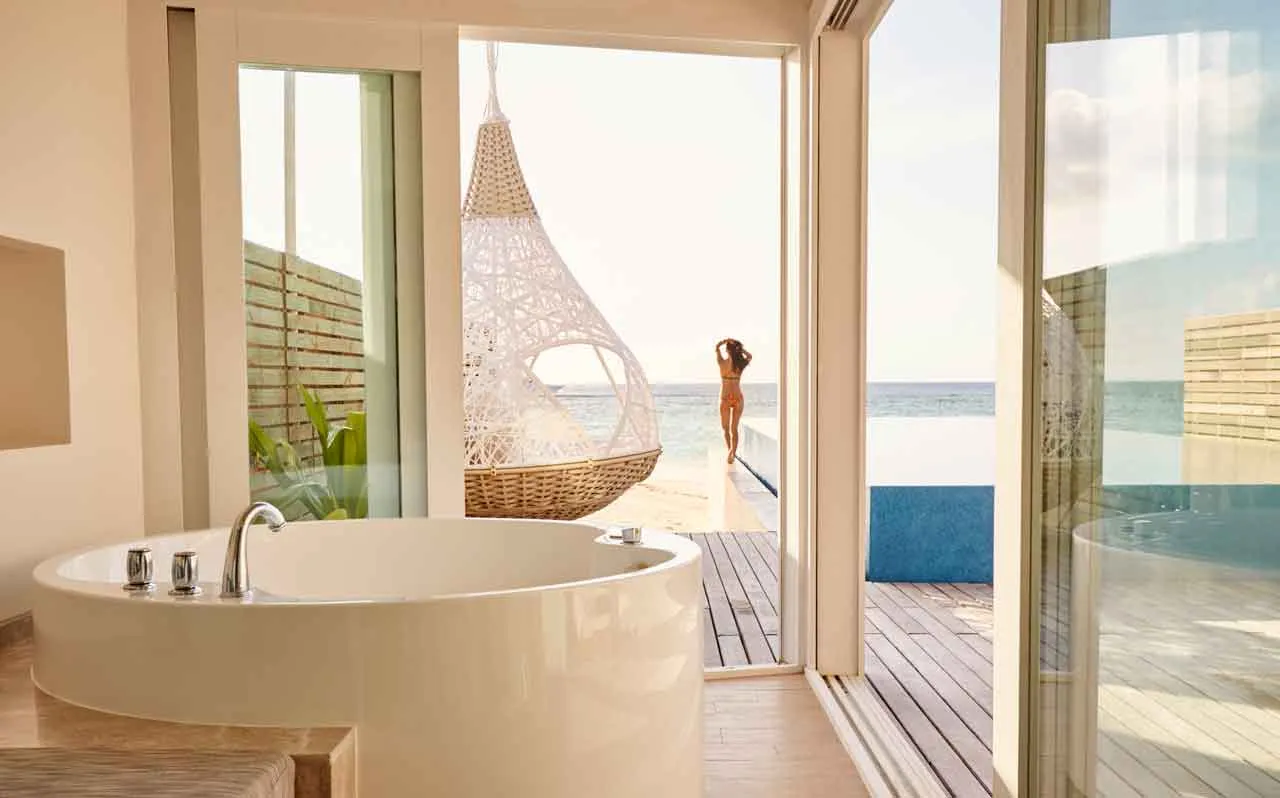 A Temptation Pool Water Villa’s round tub, the door open to the deck and the sea