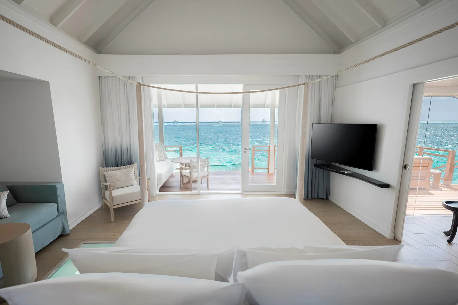 A refurbished Water Villa bedroom, its glass doors onto the lagoon