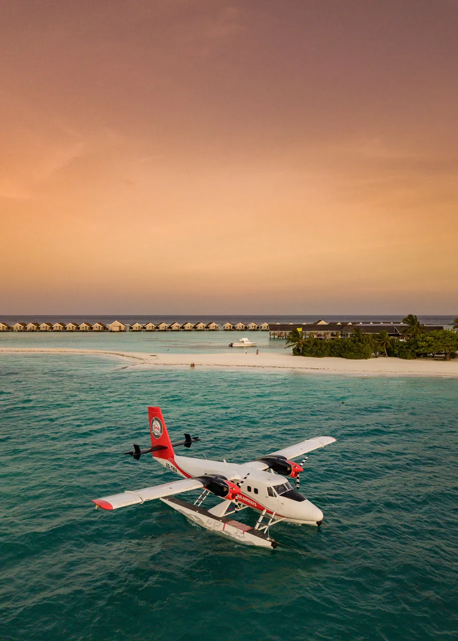 A seaplane on the lagoon at sunset, the island behind