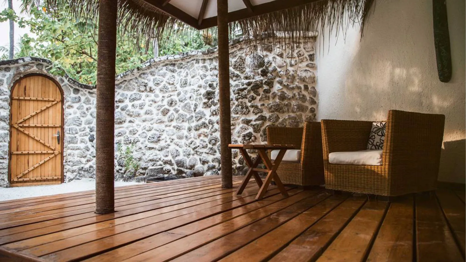 A Garden Villa’s timber patio, with armchairs and the coral wall that encloses the garden.