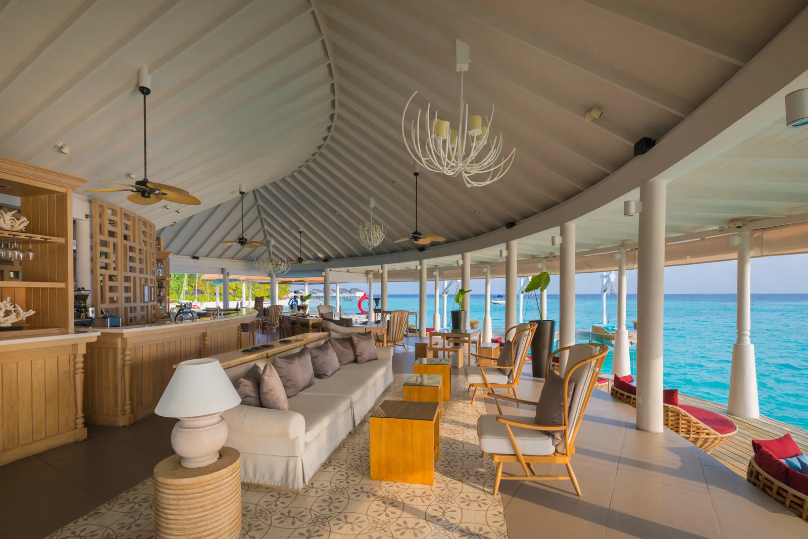 Aqua Bar: the counter, the white sofa and the armchairs under the curved roof, open to the lagoon.