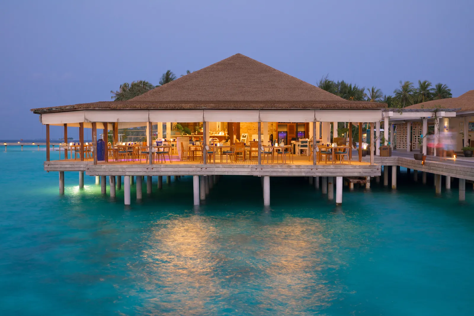 Mare Azzurro at dusk, the lit pavilion on stilts over the lagoon.