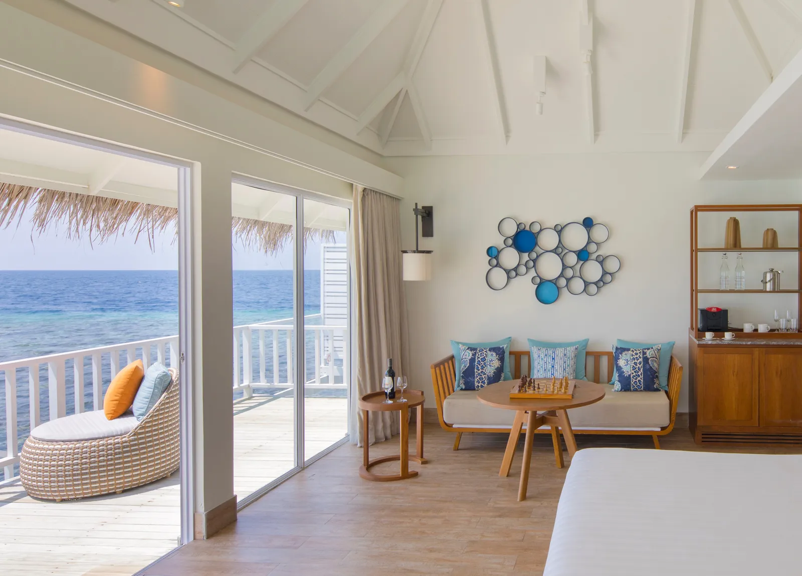 The living area of a Family Overwater Villa: the sofa, the low table and the glass door to the deck over the sea.