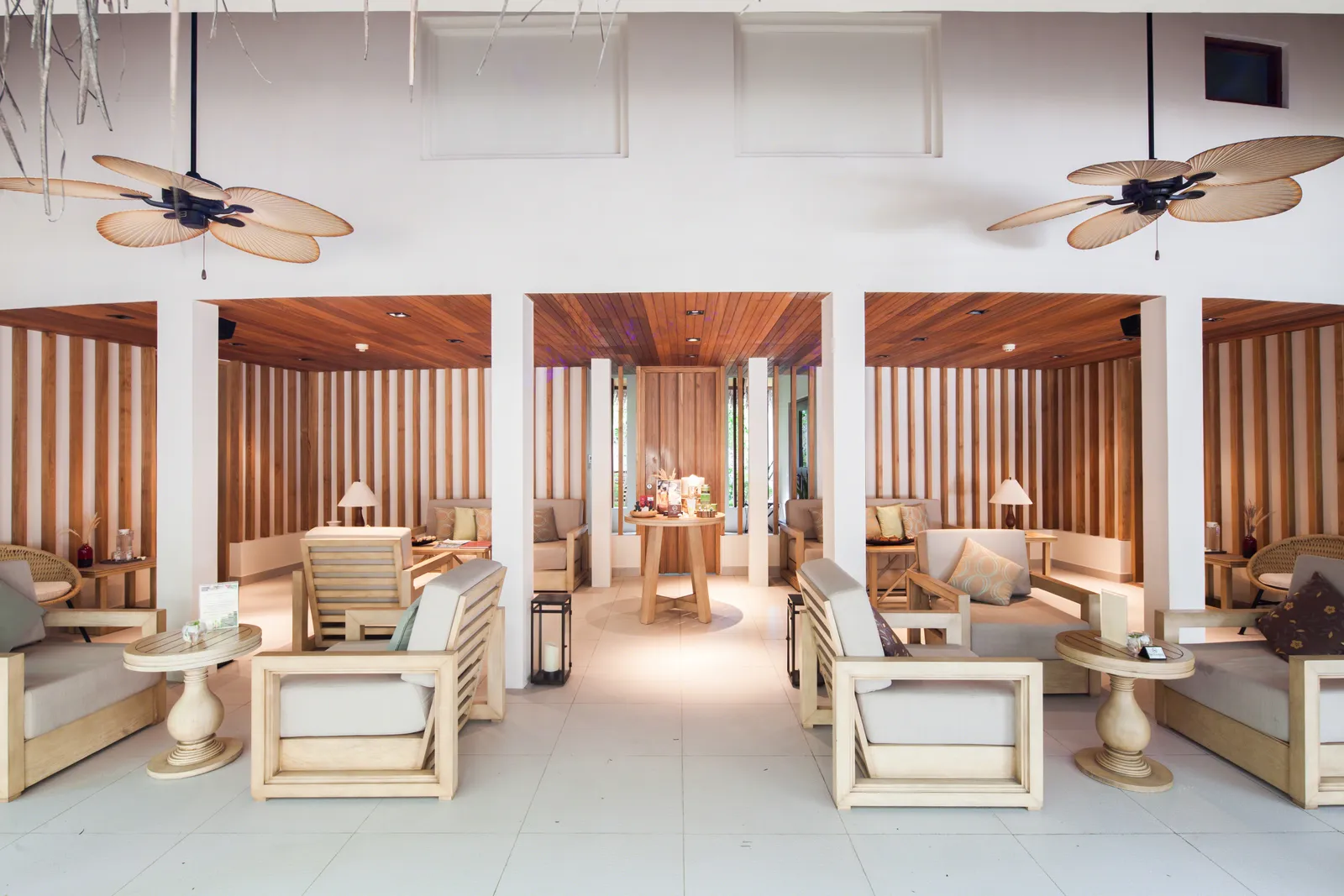 The SPA Cenvaree lounge: white armchairs between slatted wooden walls, under the paddle fans.