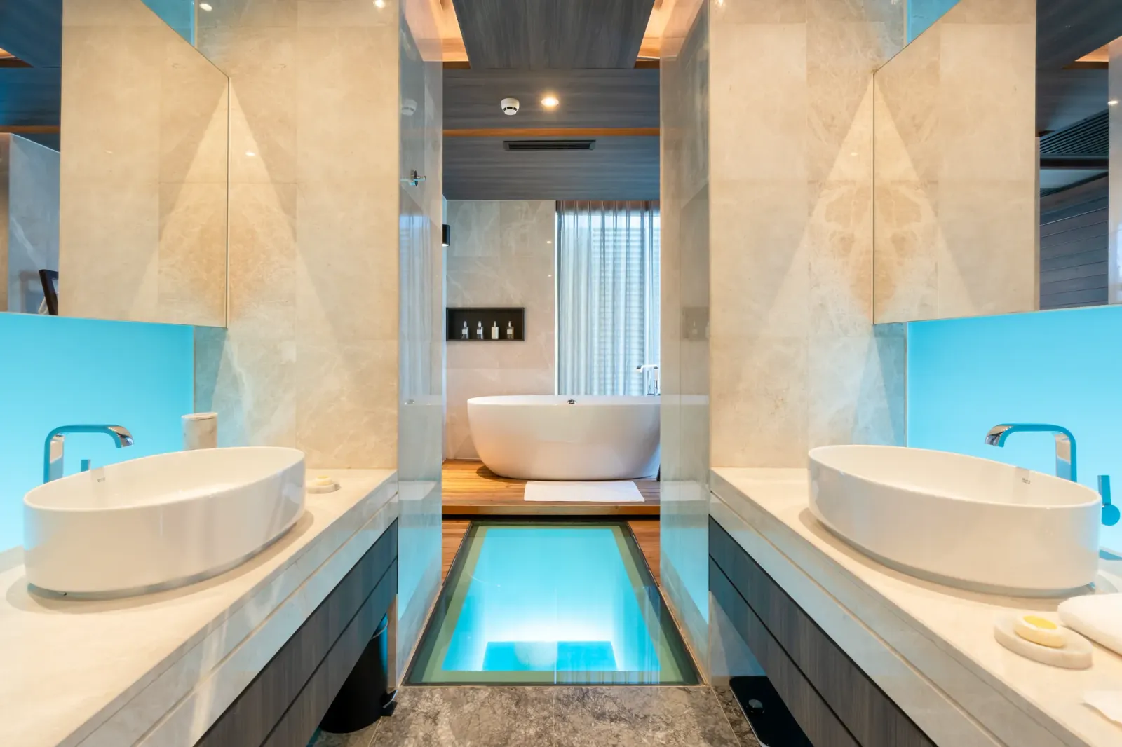 The Grand Madifushi Aqua Pool Villa’s bathroom: 2 basins, the bathtub at the end and the glass floor over the lagoon.