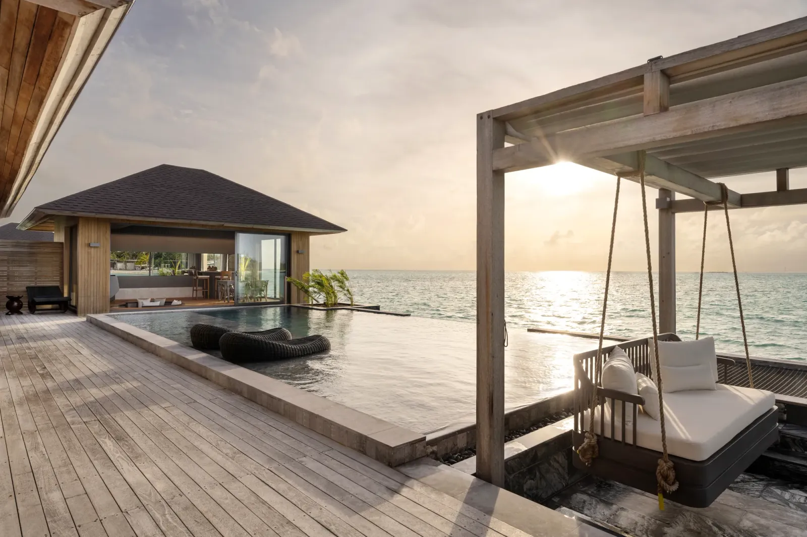 A Tranquil Aqua Pool Villa’s deck at sunset, with the infinity pool and the swing under the pergola.