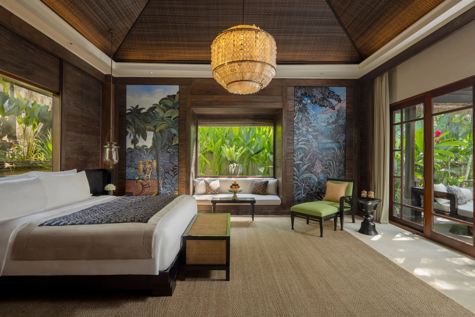 The bedroom of a Riverfront Pool Villa, its king bed and glass wall on the green