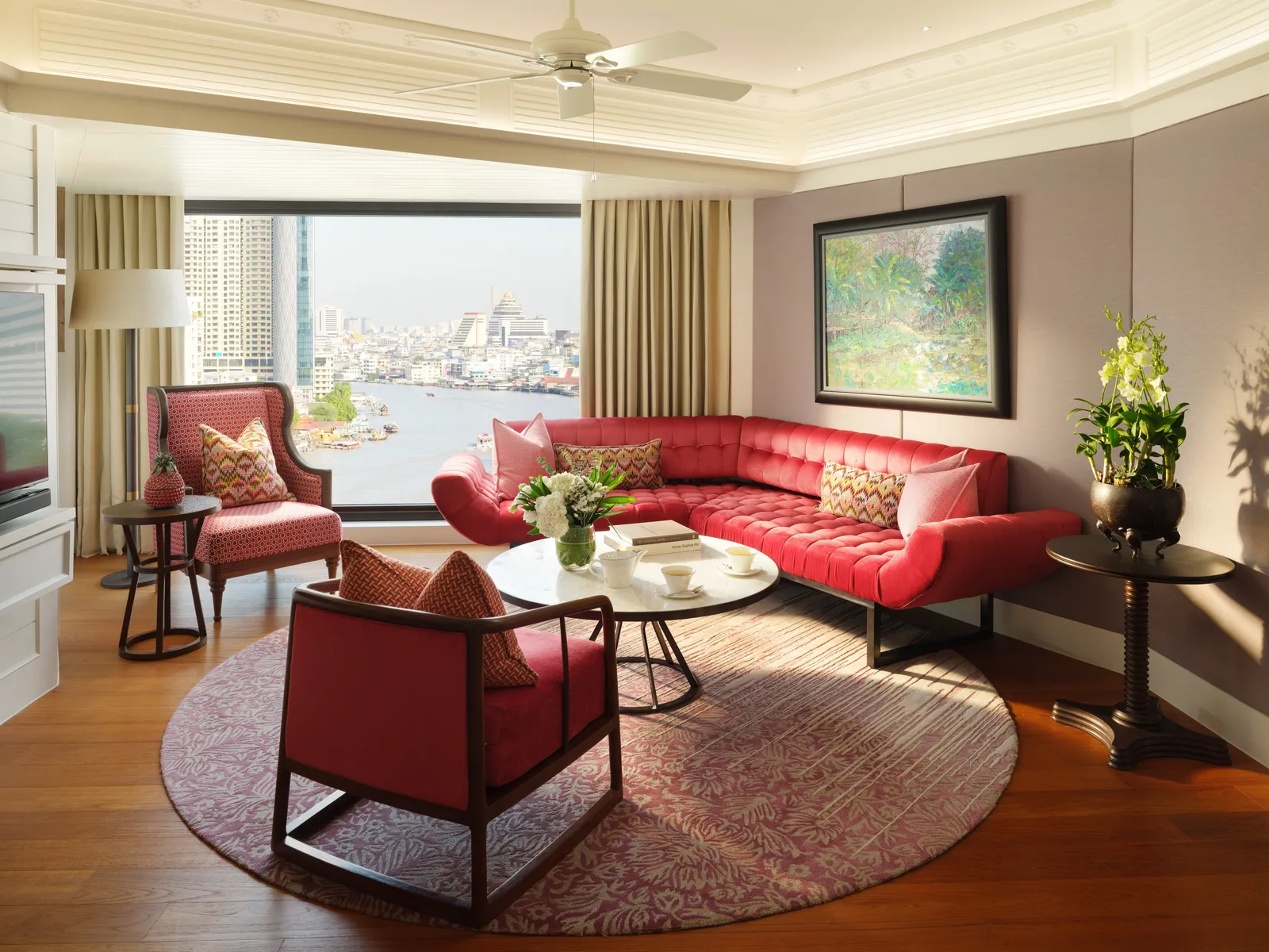 Premier One-Bedroom Suite: un divano rosso, le poltrone e il fiume oltre il vetro