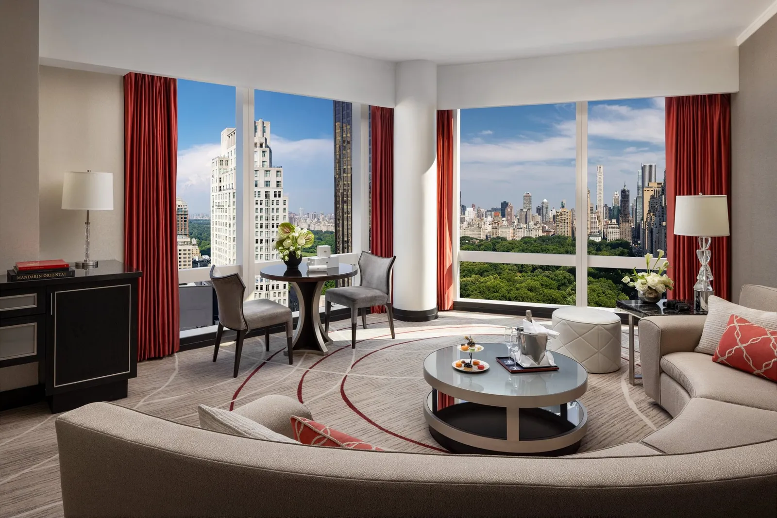 Living room with red curtains and corner windows facing the park