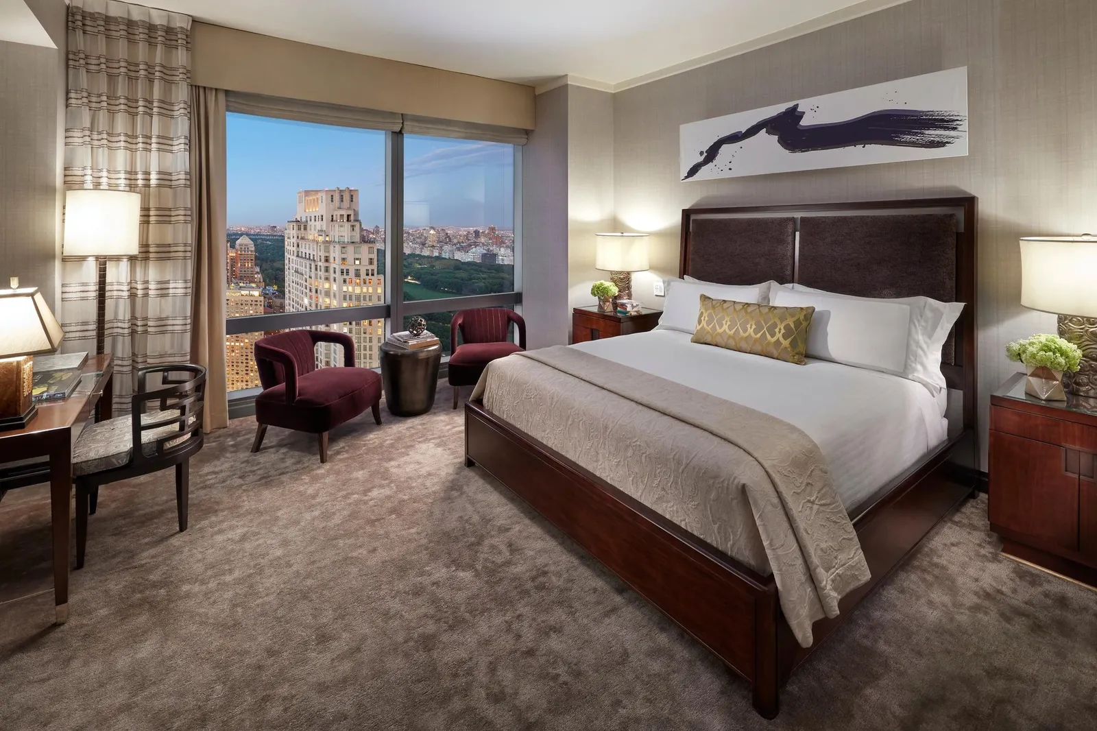 King bed and 2 burgundy armchairs beside the window