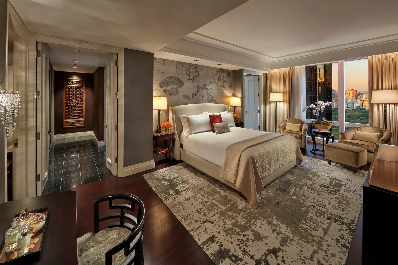 Bedroom with patterned walls, a table and a city window at dusk