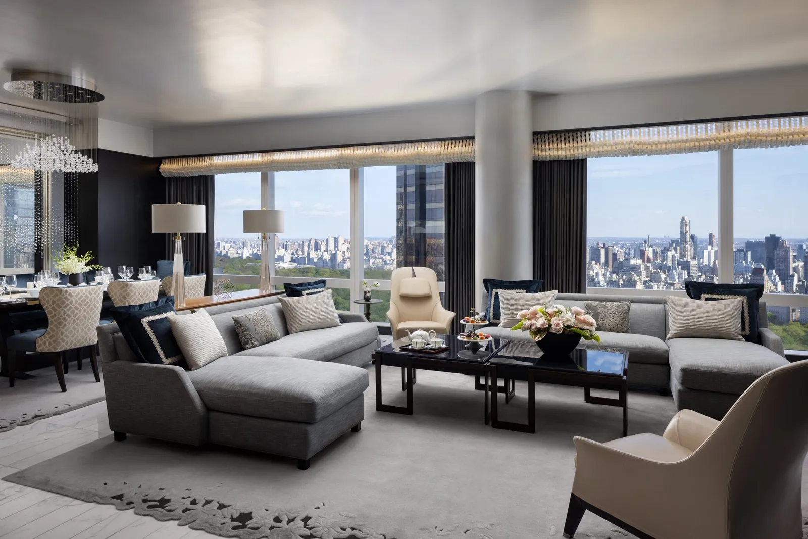 Living room with grey sofas, black tables and broad park-facing windows