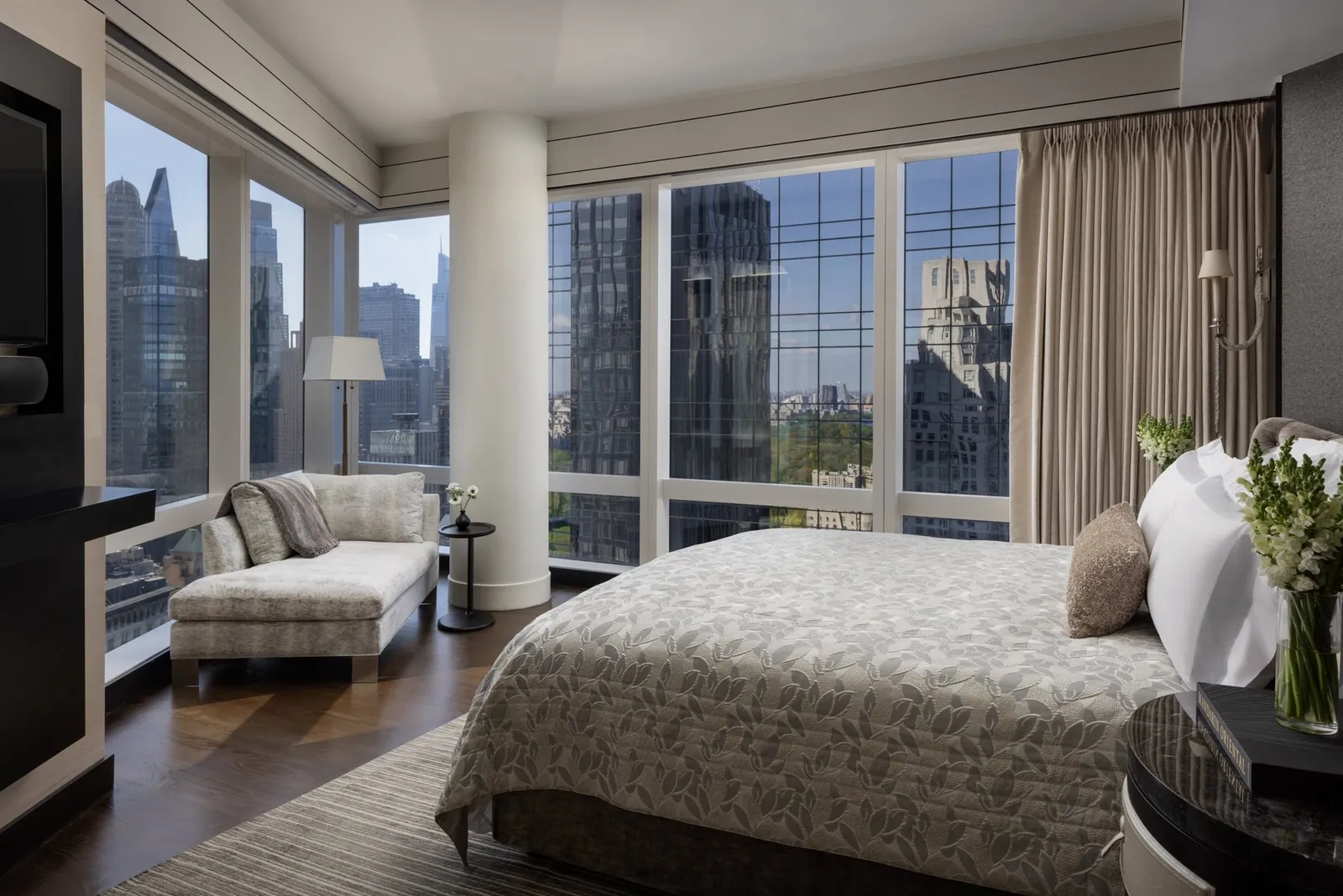 Bed and chaise longue between corner windows