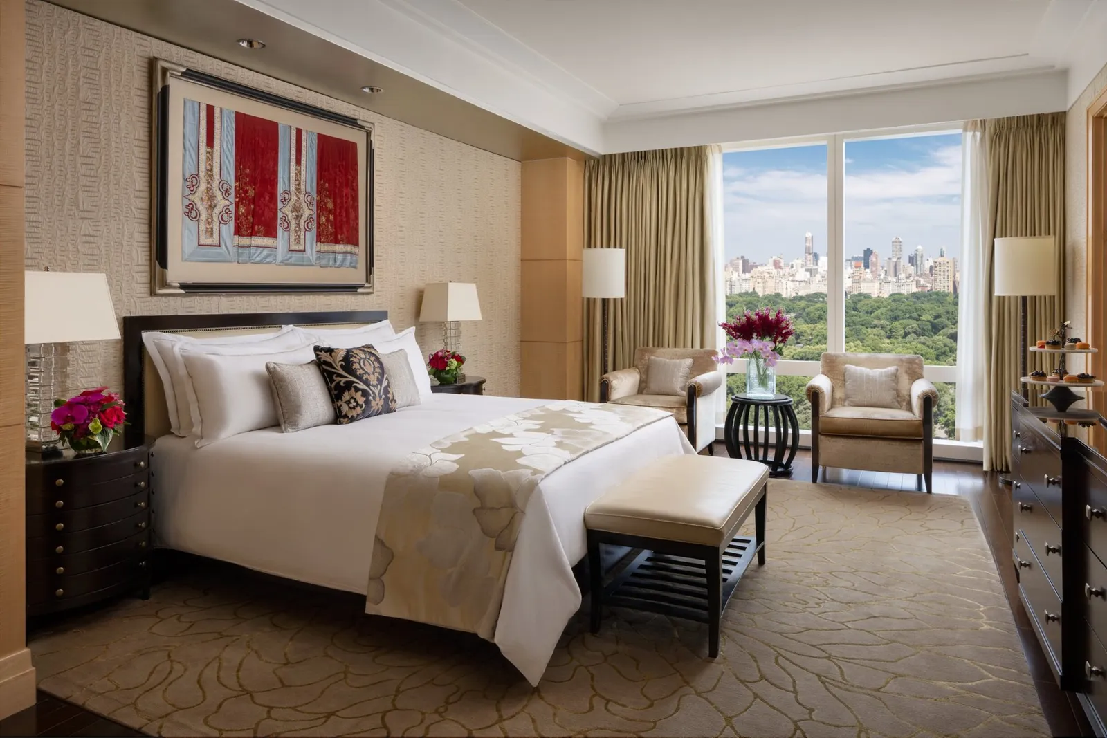 Double bed and bench beside windows facing Central Park’s greenery