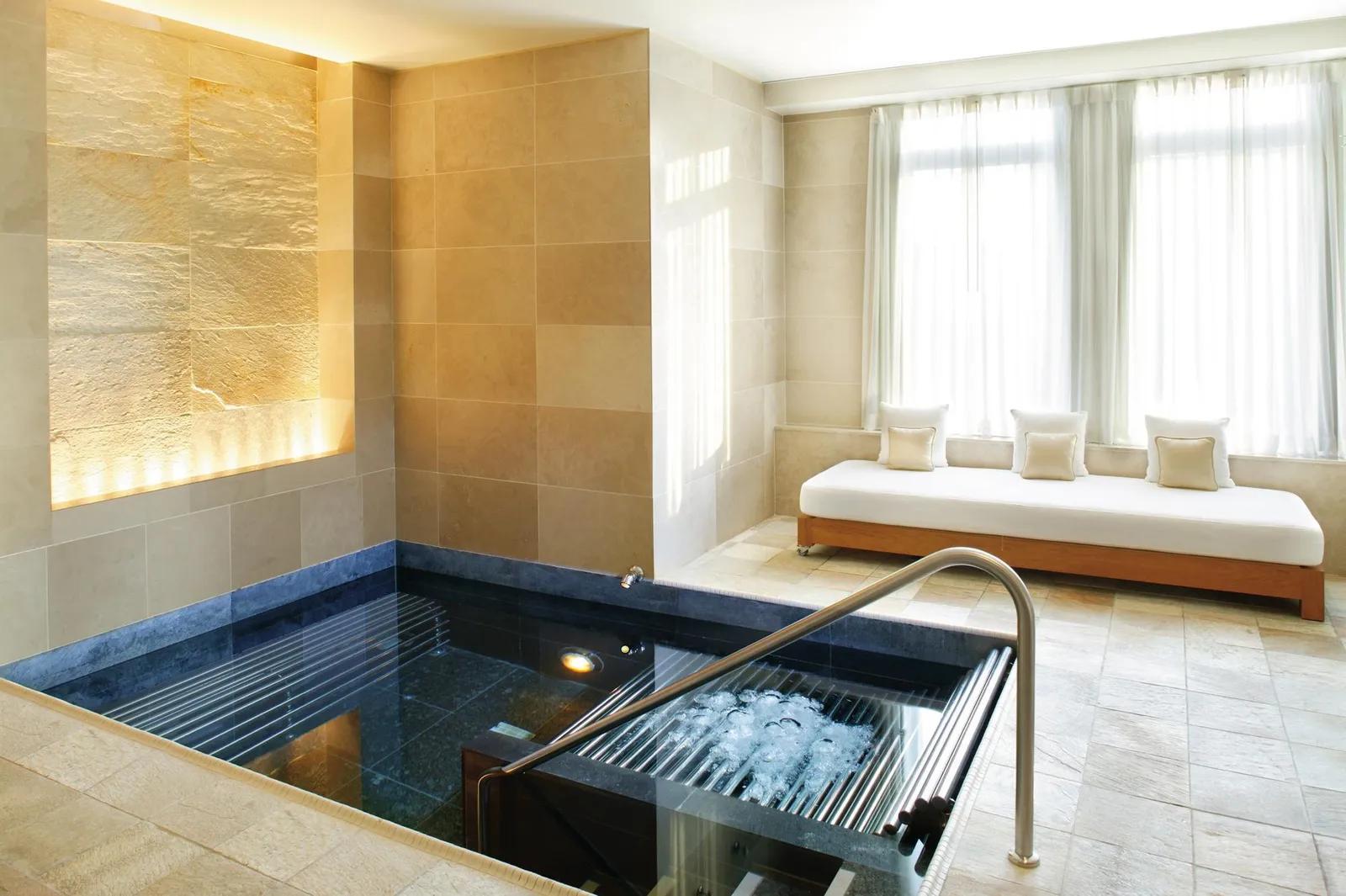 Vasca idromassaggio della spa con corrimano e divano accanto alla finestra