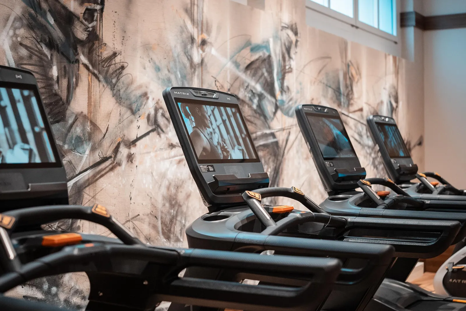 Cardio machines in front of the decorated gym wall