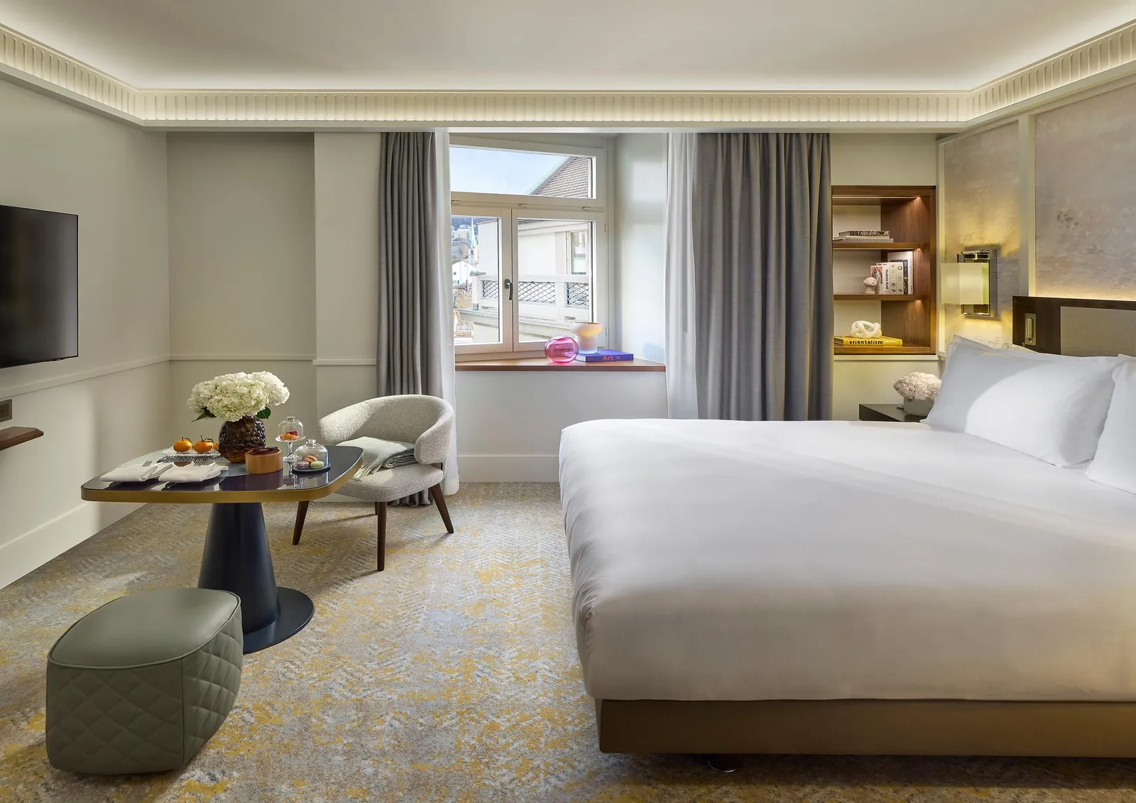 Double bed and armchairs in front of courtyard windows