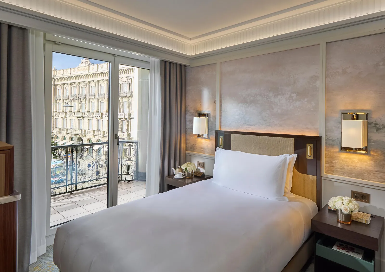 The Superior Single Room bed in front of city-facing windows