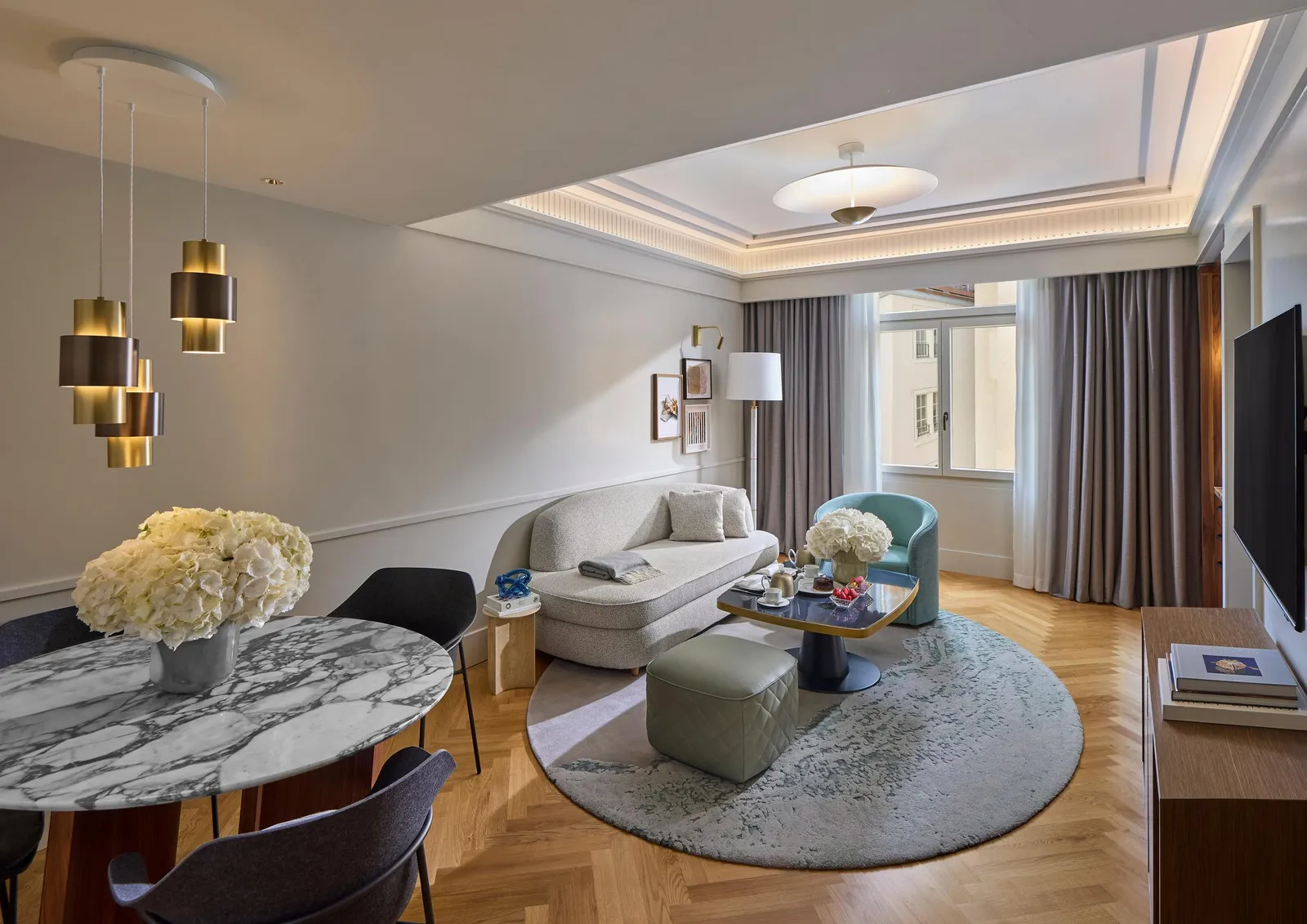 Zurich Suite sitting room with a sofa, round table and windows