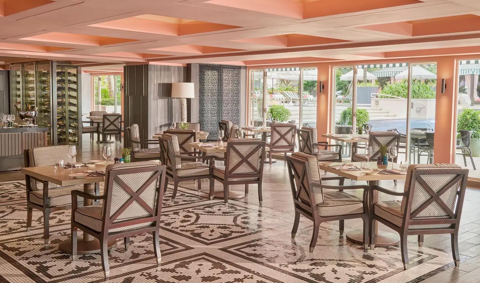 Dolce Vita’s dining room: wooden tables, cross-backed chairs, a pink coffered ceiling and windows onto the pool.