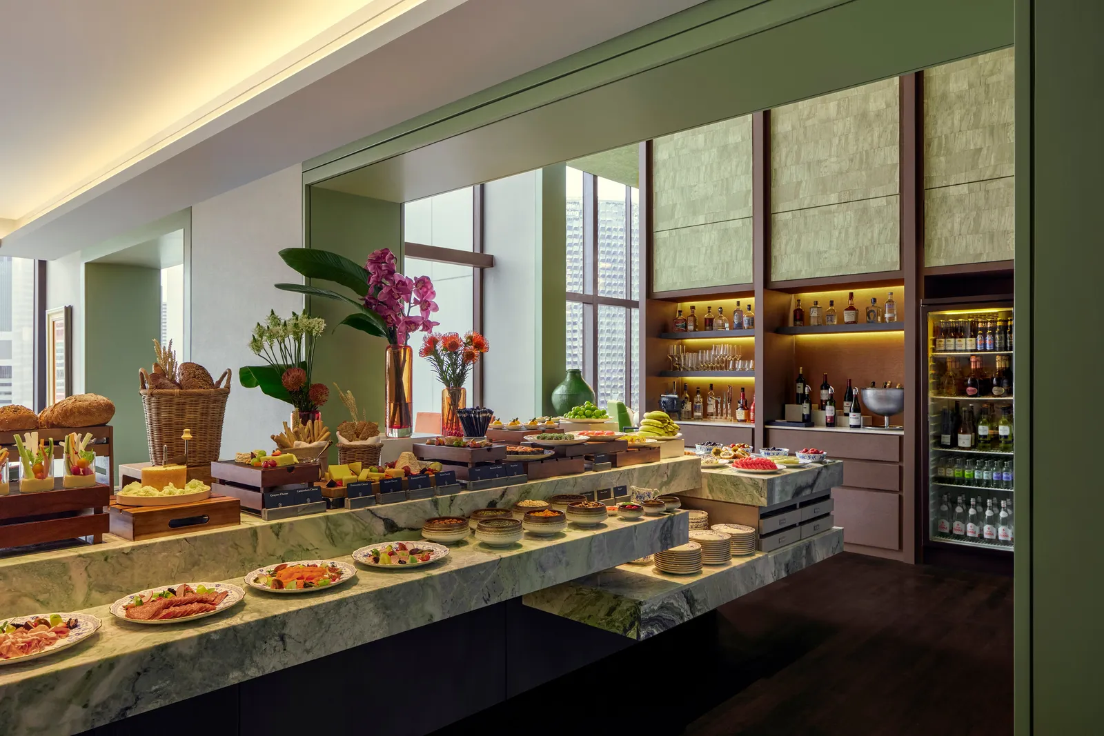The buffet at HAUS 65: dishes and bread on a green marble counter, with wines and spirits on the shelves behind.