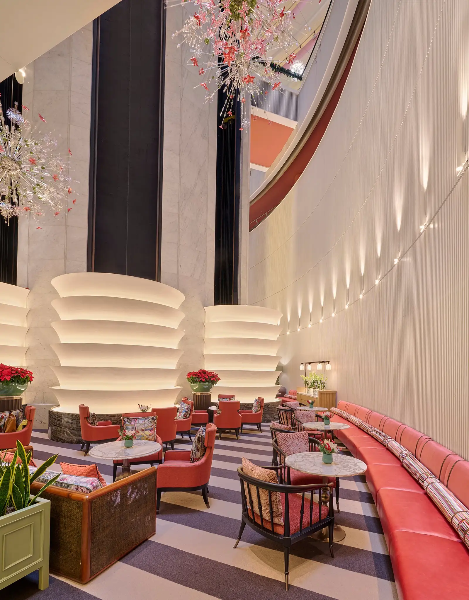 The Lobby Lounge: red armchairs and banquettes on a striped floor, under an installation of crystal flowers.